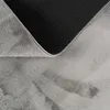 A close-up view of a folded gray rug, showing the fluffy texture of the top side and the patterned backing. Produktbild-Vorschau