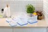 A set of clear plastic food storage containers with blue lids are arranged on a kitchen countertop. Náhled obrázku produktu
