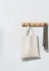 A wooden coat rack with five hooks mounted on a textured white wall. A canvas tote bag and a gray scarf are hanging from two of the hooks. Podgląd zdjęcia produktu