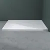 A white shower tray with a drain is shown in a bathroom setting with dark tiled walls and a concrete floor. Produktbild-Vorschau