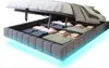 A bed frame with storage compartments open, showing folded linens and blankets inside. The bed frame has integrated LED lighting along the bottom. Produktbild-Vorschau