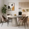 A dining room setting with a round table and chairs, a plant, and a painting on the wall. Produktbild-Vorschau