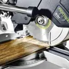 A close-up view of a miter saw cutting a wooden plank. Podgląd zdjęcia produktu