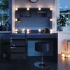 A vanity table with LED lights and a stool in a dimly lit room, with a window showing a snowy mountain landscape. Produktbild-Vorschau