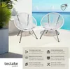 Two white Acapulco-style garden chairs on a patio overlooking the ocean. Náhled obrázku produktu