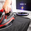 A person's hand is holding a cordless iron over a dark gray fabric, with a charging base visible on an ironing board. Anteprima dell’immagine prodotto