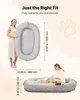 A woman is holding a large oval pet bed, and another woman is petting a dog on a similar bed. The image highlights the size and coziness of the pet bed. Anteprima dell’immagine prodotto