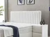 A white boxspring bed with a fluted headboard is shown in a bedroom setting. Produktbild-Vorschau