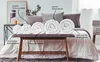 Rolled up duvets/quilts displayed on a bench in front of a bed. Voir les images du produit