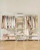 A white metal garment rack with multiple shelves, filled with clothing, bags, hats, shoes, and boxes. Náhled obrázku produktu