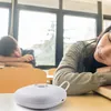 Two students sleeping at desks in a classroom with a white alarm clock in the foreground. Podgląd zdjęcia produktu