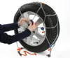 A person's hands are shown attaching snow chains to a car tire. Produktbild-Vorschau