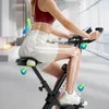 A woman is using a foldable exercise bike indoors, with anatomical diagrams highlighting posture and joint alignment. Anteprima dell’immagine prodotto