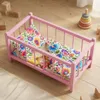Ein hölzernes Puppenbett in Rosa mit Bettwäsche im Produktbild-Vorschau 2