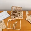 A wooden mechanical model kit and its unassembled parts are laid out on a wooden table. Podgląd zdjęcia produktu