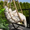 A hanging chair on a balcony with greenery in the background. Produktbild-Vorschau