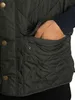 A close-up shot of a person's hand reaching into the pocket of a quilted vest. Produktbild-Vorschau