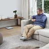 A man is sitting on a couch eating cereal, with a bathroom scale visible on the floor. Podgląd zdjęcia produktu