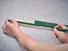 A person is using a Bosch measuring tool on a piece of wood. Produktbild-Vorschau
