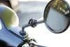 A close-up shot of a motorcycle mirror mount attached to the handlebar of a scooter. Náhled obrázku produktu