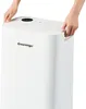 Hands holding the top of a white dehumidifier. Produktbild-Vorschau