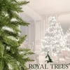 A close-up of a Christmas tree branch in the foreground, with a softly lit room with decorated Christmas trees and gifts in the background. Voir les images du produit
