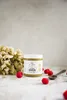 A jar of pistachio cream is placed on a surface with raspberries and a wooden spoon. Produktbild-Vorschau