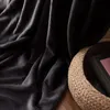 A close-up of a dark gray blanket draped over a woven basket containing a book. Anteprima dell’immagine prodotto