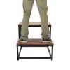 A person's legs and feet are shown standing on a two-step ladder. Podgląd zdjęcia produktu