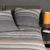 A close-up view of a bed with striped bedding and pillows. Produktbild-Vorschau