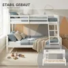 A white bunk bed with blue and beige bedding, set in a room with a geometric mountain-themed wallpaper. Toys are scattered on the floor in front of the bed. Náhľad obrázku produktu