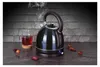 A black electric kettle is shown steaming, next to a glass of red tea, on a dark countertop with scattered dried petals. Náhled obrázku produktu