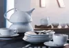 A white porcelain tea set is arranged on a dark surface, with a teapot, cups, saucers, and plates visible. Anteprima dell’immagine prodotto