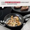 Two frying pans are on a stovetop, one with steaks and the other with fried onions. Text overlays indicate suitability for all stovetops, including induction. Produktbild-Vorschau