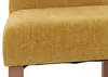 A close-up view of the seat and side of a yellow fabric dining chair with natural wood legs. Náhled obrázku produktu