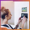 A woman is interacting with a digital weather station and control panel mounted on a wall. Anteprima dell’immagine prodotto