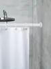 A close-up view of a white shower curtain rod with a white shower curtain hanging from it, in a bathroom with gray tiled walls. Produktbild-Vorschau