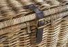 A close-up view of a woven basket with a leather strap and buckle. Podgląd zdjęcia produktu