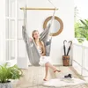A woman is relaxing in a hanging chair on a porch, with plants and umbrellas visible in the background. Produktbild-Vorschau