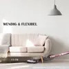 A cordless stick vacuum cleaner is shown being used under a sofa, demonstrating its maneuverability and low profile capability. Produktbild-Vorschau