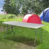 A folding table is set up on grass in a campsite with tents in the background. Náhľad obrázku produktu