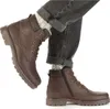 A person wearing brown leather boots and dark jeans. Produktbild-Vorschau