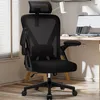 A black ergonomic office chair with a headrest is shown in a home office setting. Produktbild-Vorschau