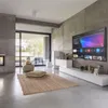 A modern living room with a large TV mounted on a concrete wall, a white media console, and a rug on the floor. Produktbild-Vorschau