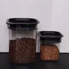 Two clear plastic storage containers with black lids, filled with food items, sit on a black surface against a light gray tiled background. Náhľad obrázku produktu