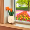 A plush toy of tulips in a pot sitting on a windowsill with a blurred background of a tulip field. Produktbild-Vorschau