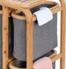 Close-up of a bamboo laundry basket with three gray fabric bins, one white towel draped over the edge, and a pink towel visible at the bottom. Produktbild-Vorschau