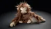 A plush toy monkey with shaggy brown fur and a grumpy expression sits on a dark, reflective surface. Náhled obrázku produktu