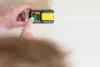 A person's hands are using a green laser level on a wall. Produktbild-Vorschau