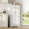 A white kitchen cabinet with double doors stands in a room with a window showing a garden view. Anteprima dell’immagine prodotto